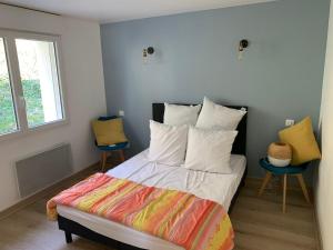 a bedroom with a bed with colorful sheets and two chairs at Confortable appartement vue lac de Pareloup in Arvieu