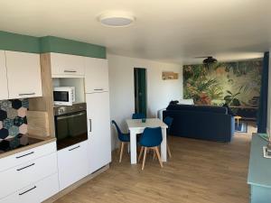a kitchen and living room with a table and a couch at Confortable appartement vue lac de Pareloup in Arvieu