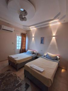 two beds in a room with lights on the wall at El Agamy Hotel Apartment in Luxor