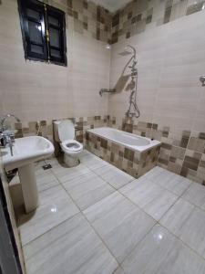 a bathroom with a tub and a toilet and a sink at El Agamy Hotel Apartment in Luxor