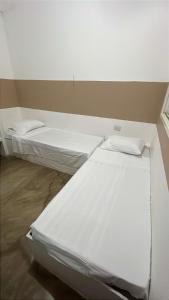 two white beds in a room with a wall at Casa ampla e completa a poucos passos da praia! in Itamaracá +10 photos