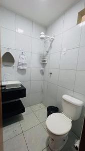 a white bathroom with a toilet and a sink at Vitallino Apartment | Modern with A/C, 10 min from the City Center in Caruaru