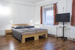 a bedroom with a bed and a flat screen tv at Bázis Vendégház Hajdúnánás in Hajdúnánás
