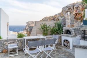 a patio with a table and chairs and a stone fireplace at Lindos 4 me Apartment in Lindos