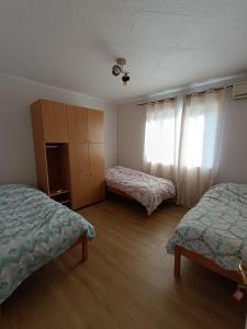 a room with two beds and a cabinet and windows at Zenith Apartment in Bitola