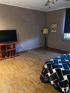 a living room with a flat screen tv and a bed at Departamento cómodo y totalmente equipado, ideal para familias, grupos o viajes laborales in Santa Fe