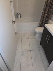 a bathroom with a tub and a toilet and a sink at Condo with grey sofa bed in Port Hope