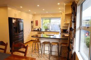 a kitchen with a black refrigerator and bar stools at Rev it up Homestay in Feilding