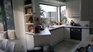 a kitchen with white cabinets and a sink and a window at logies Huis Liselotte in Genk