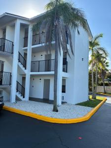 a white building with palm trees in a parking lot at Nova Inn Resort in Boynton Beach