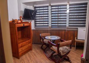 a living room with a table and chairs and a television at Hotel La Castellana in Santiago