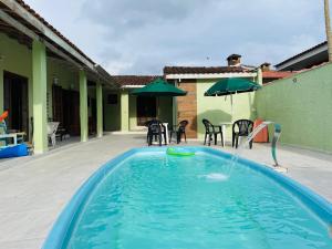 a swimming pool with a table and chairs and an umbrella at Pousada NASCER DO SOL in Bertioga