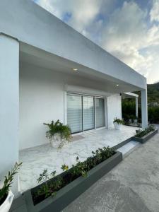 a white house with a patio with plants at Modern Ocean View Apartment in Upper Prince's Quarter