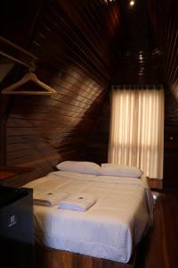 a bedroom with a bed with white sheets and a window at Alpinas Natural Suites in Lunahuaná +75 photos