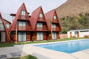 a house with a swimming pool in front of it at Alpinas Natural Suites in Lunahuaná