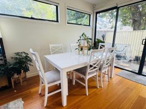 a white dining room with a white table and chairs at Quiet and Cozy corner in Braybrook +2 photos