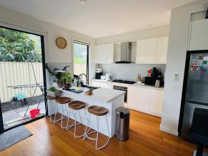 a kitchen with white cabinets and a counter with stools at Quiet and Cozy corner in Braybrook