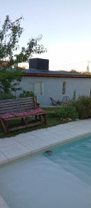 a wooden bench sitting next to a swimming pool at Casa Sol Naciente in Villa Santa Cruz del Lago