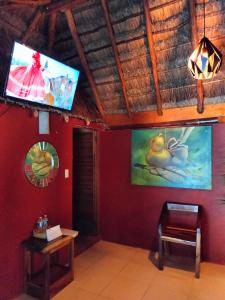 a room with a tv and a red wall at Hotel Aldea Cruzo'ob in Felipe Carrillo Puerto