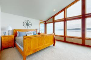 a bedroom with a wooden bed and windows at Whalehouse in Tyee Beach