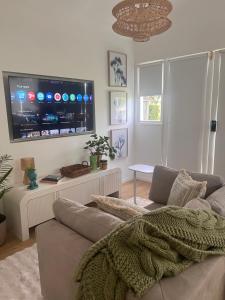 a living room with a couch and a flat screen tv at Frankie's on Frank in Scarborough
