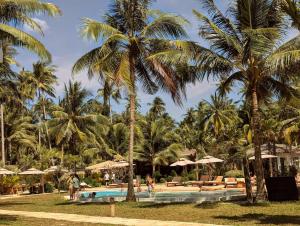 a pool at a resort with palm trees and umbrellas at Mint Lotus Resort - Koh Kood in Ban Bang Bao