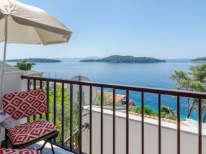a balcony with an umbrella and a chair and the ocean at Apartments by the sea Prizba, Korcula - 12648 in Prizba