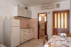 a kitchen with a table and a white refrigerator at Apartments by the sea Prizba, Korcula - 12648 in Prizba