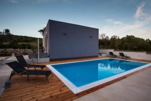 a swimming pool on a wooden deck with chairs around it at Apartment Verunic 14286d in Veli Rat