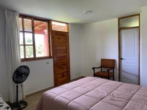 a bedroom with a bed and a window and a chair at La Casona - Hospedaje Campestre in El Carmen