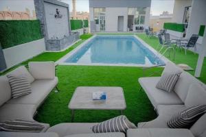 a swimming pool with couches and a table and a table at chalet B1 in Al Khīrān