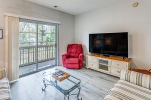 a living room with a flat screen tv and a red chair at Condo w/ Pool Access, 1 Mi to Cherry Grove Beach in Myrtle Beach