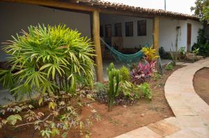 a garden with plants and a hammock in front of a house at Casarão Duque do Mel in João Pessoa