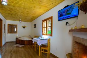 a dining room with a table and a tv on the wall at Pousada Varanda Colibri in Monte Verde
