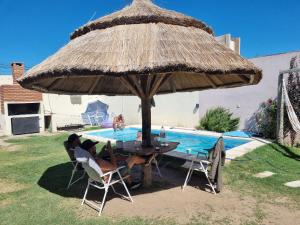 two people sitting at a table under an umbrella by a pool at El jacaranda Alojamiento Diario in San Luis