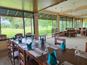 a dining room with wooden tables and chairs with blue napkins at Wilpattu Tree House in Wilpattu