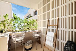 a balcony with chairs and a wall with plants at Beachfront 2BR Condo in Bahía Tankah, Tulum in Tancah