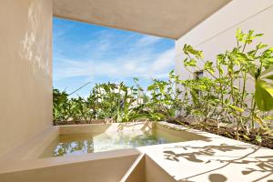 a bath tub sitting next to a window with plants at Beachfront 2BR Condo in Bahía Tankah, Tulum in Tancah