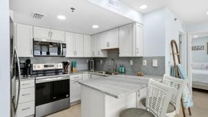 a kitchen with white cabinets and a counter top at Steps to the beach and amazing views! in Panama City Beach