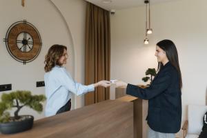 Zwei Frauen schütteln sich in einem Zimmer über einen Tisch hinweg die Hände. in der Unterkunft Hotel Dado in Grude + 68 Fotos