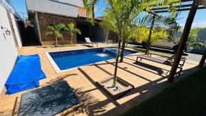 a swimming pool with a palm tree and a house at Rancho Paradise Aruanã GO in Aruanã