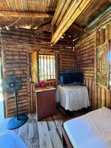 a room with a bed and a table in a log cabin at Cabañas Aires de mi campo in Paicol