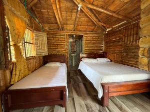 a bedroom with two beds in a log cabin at Cabañas Aires de mi campo in Paicol