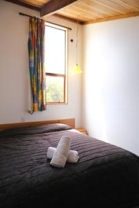 a bedroom with a bed with a blanket and a window at Forest Trail Lodge in Hanmer Springs