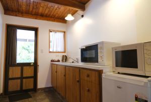 a kitchen with a microwave and a television on a counter at Forest Trail Lodge in Hanmer Springs