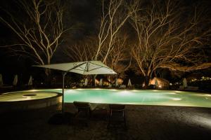 a pool with an umbrella and chairs at night at Holistic EcoHotel in Santa Fe de Antioquia