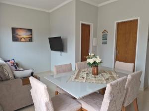 a dining room table with a vase of flowers on it at Casinha Encantada da MaLu in Itapema +7 photos