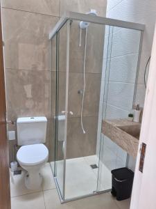 a bathroom with a shower with a toilet and a sink at Casinha Encantada da MaLu in Itapema