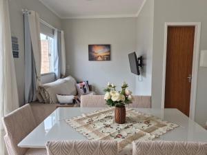 a dining room table with a vase of flowers on it at Casinha Encantada da MaLu in Itapema