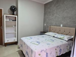 a bedroom with a bed and a book shelf at Casinha Encantada da MaLu in Itapema